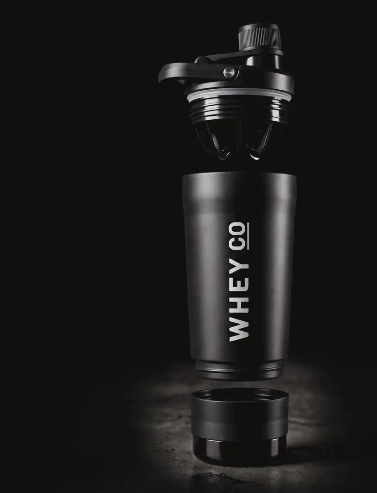 The Whey Co Matte Black Shaker — exploded view showing integrated whisk, double-wall insulated body, and storage compartment